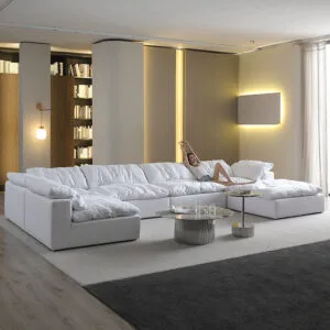 Woman Stretching on Large White Cloud Sectional Sofa Image 1 ALT Text: A woman in a white tank top and denim shorts stretches languidly on a large, plush white cloud sectional sofa in a modern living room.